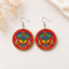 Traditional goddess face wooden earrings with red and gold folk art design