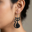 Black wooden drop earrings shaped like a sitting cat silhouette with heart cutouts for eyes