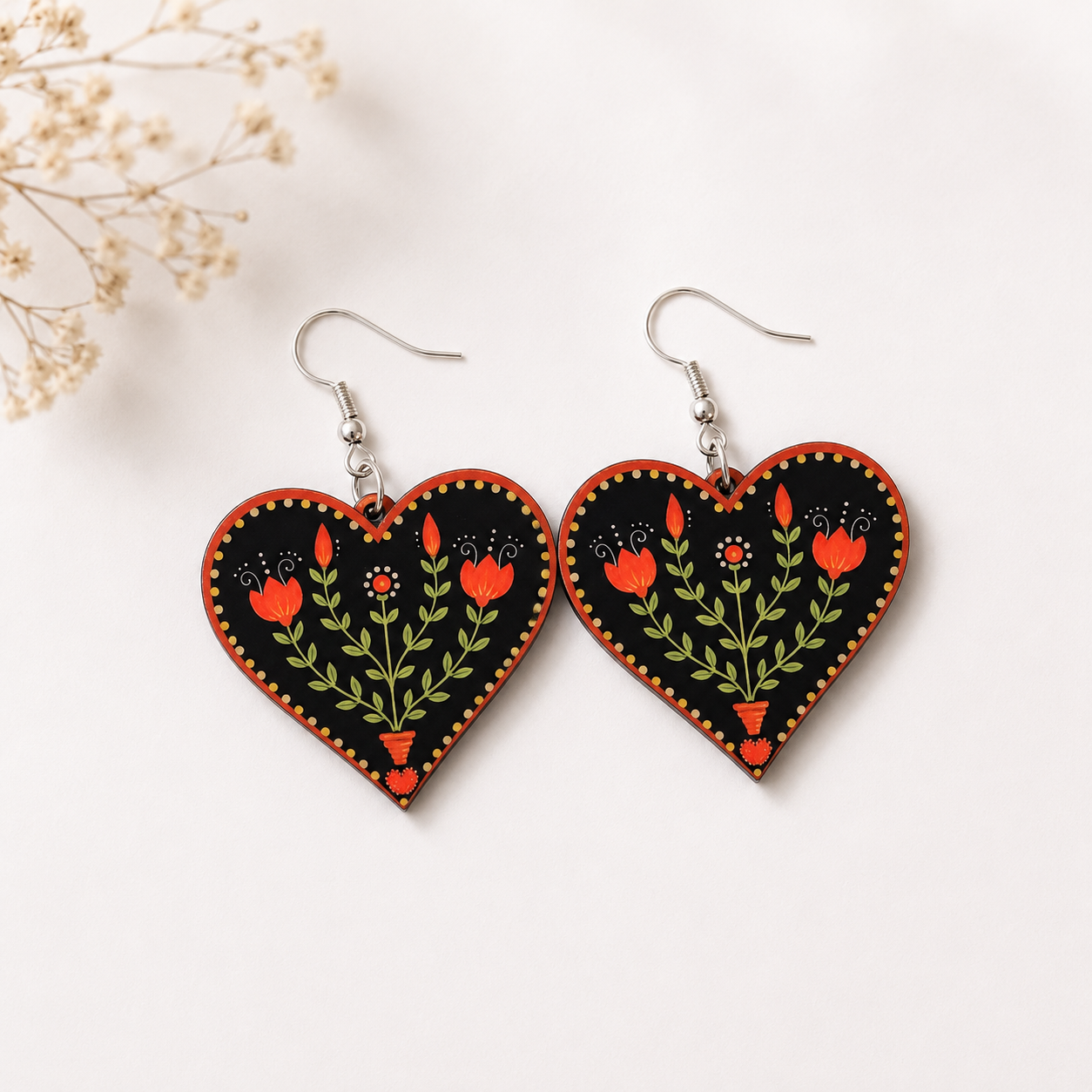 Black heart-shaped wooden earrings with hand-painted red tulip floral folk art design

