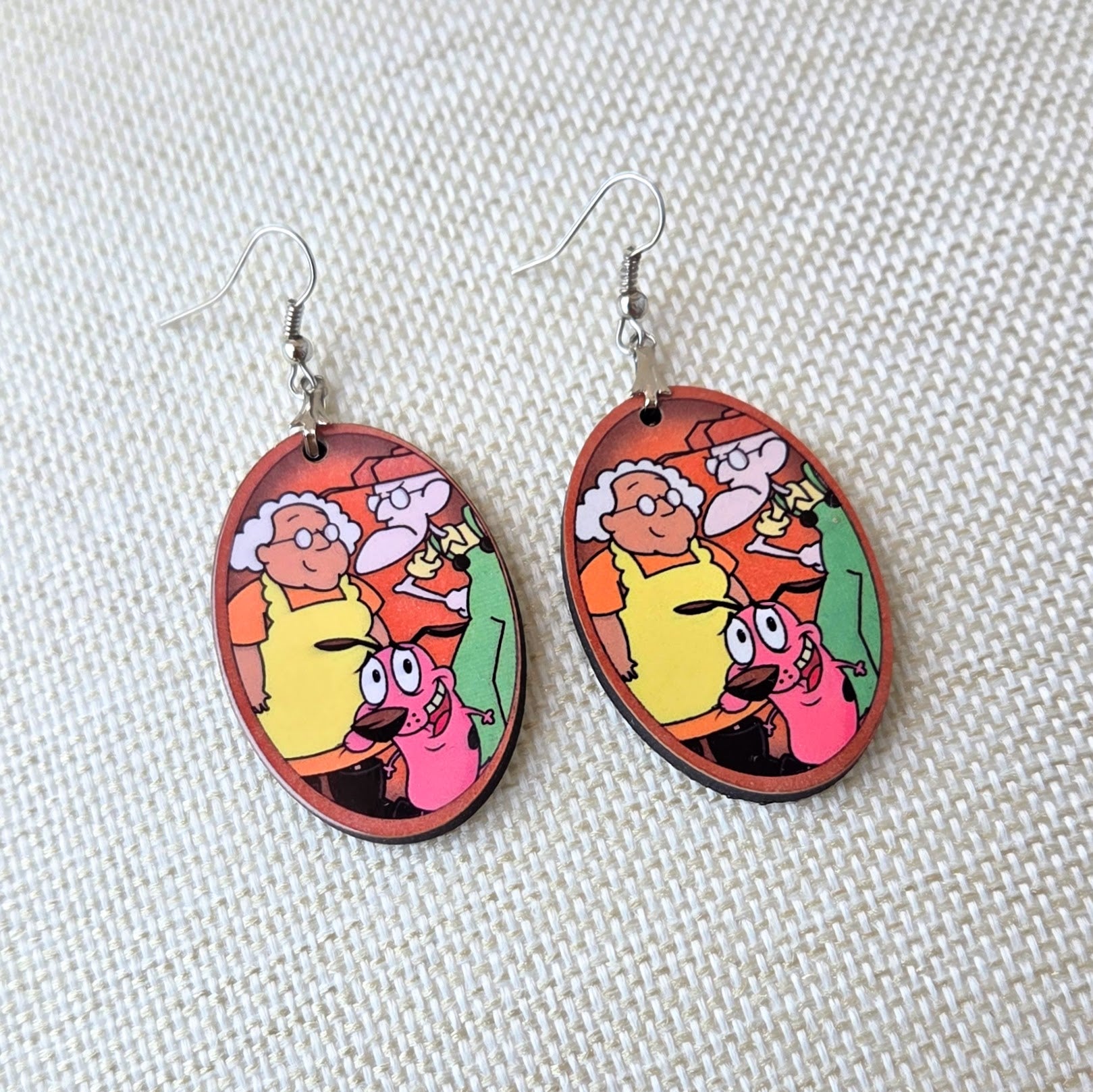 Courage the Cowardly Dog wooden earrings featuring Courage, Muriel, and Eustace in a colorful oval design with lightweight fish hook ear wires. Main image
