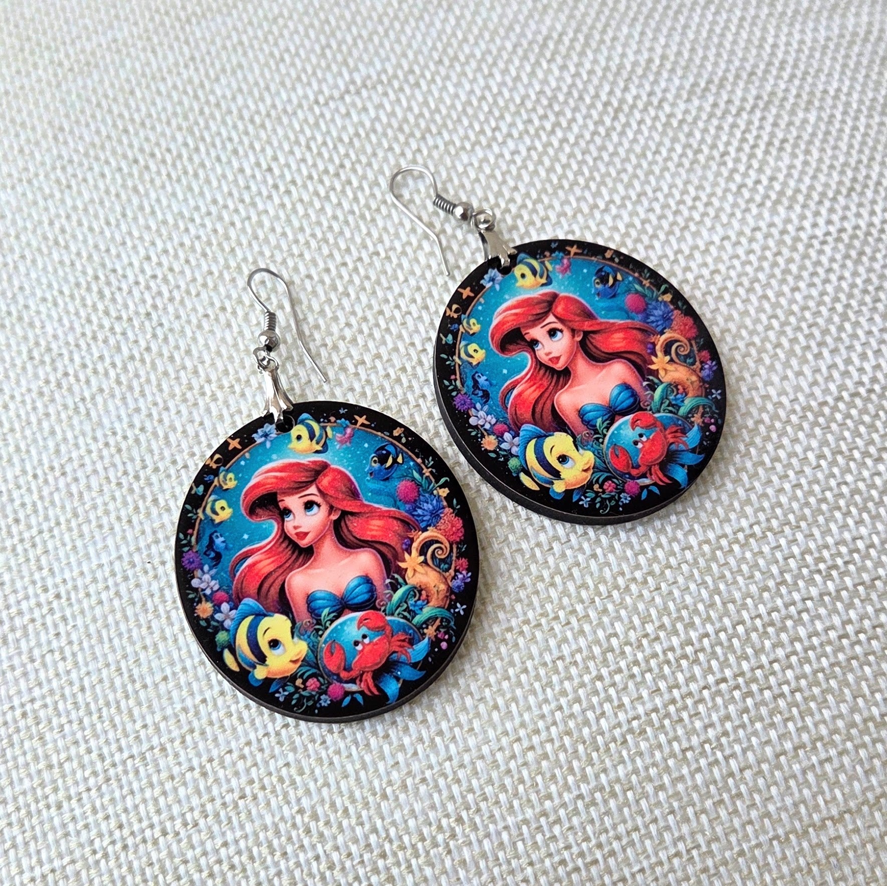 Disney Princess Ariel wooden earrings featuring Ariel with Flounder, Sebastian, and colorful underwater sea life in a round lightweight design with fish hook ear wires. Main image