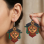 Woman wearing vibrant, colorful wooden dangle earrings featuring a traditional painted design of Goddess Durga's face.