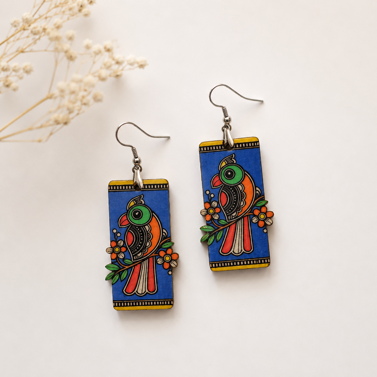 Handcrafted Madhubani art wooden earrings for women featuring colorful bird and floral folk artwork on a blue rectangular design. Main image