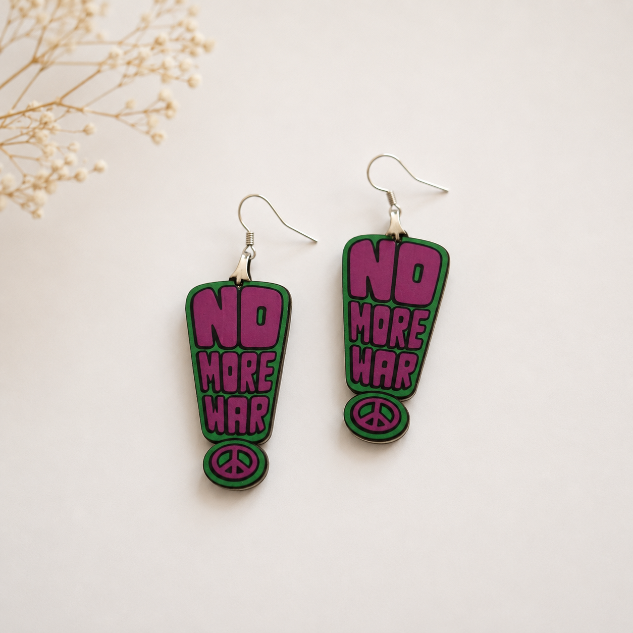 Handcrafted No More War wooden earrings for women with retro typography design and peace symbol on a minimal neutral background. Main image