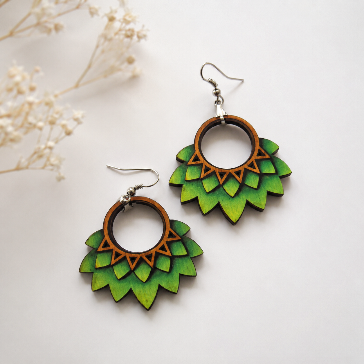 Handcrafted lotus bloom wooden earrings with layered green petal design and silver hooks on a minimal neutral background. Main image