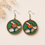 Lovebirds wooden earrings for women featuring colorful birds perched on a tree branch with lush green foliage in a circular nature-inspired design.