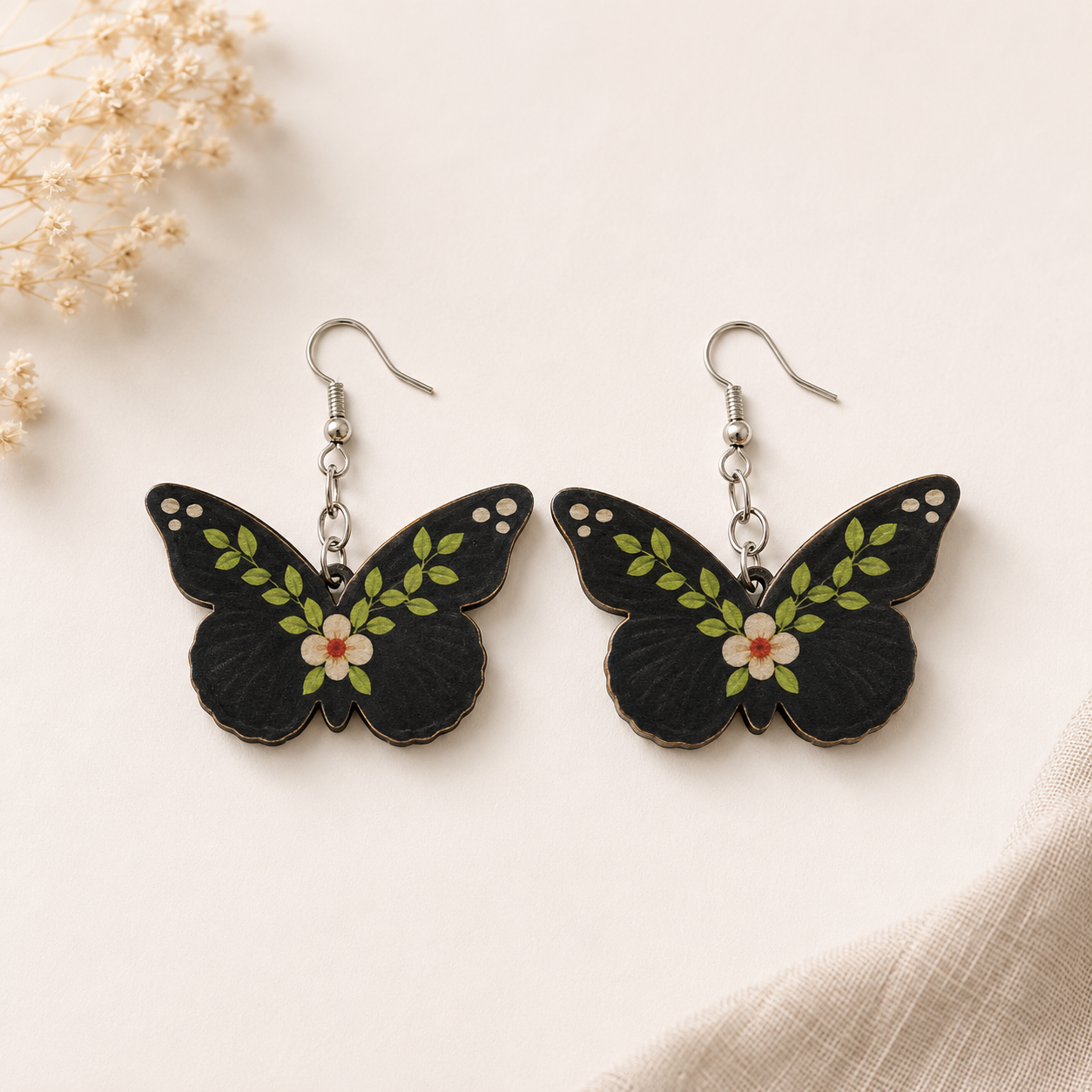 Midnight Butterfly wooden earrings for women featuring a black butterfly with green leafy vines and white floral artwork on lightweight fish hook ear wires. Main image