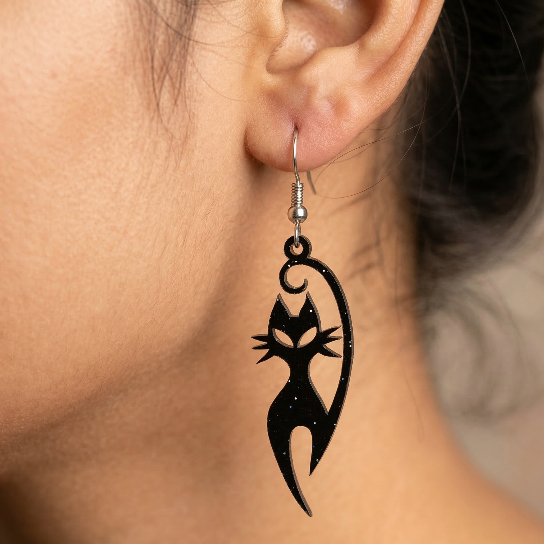 Close-up of a lightweight black cat silhouette wooden dangle earring on a silver hook, designed for women.
