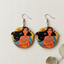 Pair of circular wooden dangle earrings for women featuring a detailed, artistic portrait of Disney's Pocahontas with wind-blown hair and a sunburst background, displayed against a neutral linen fabric with a dried leaf.